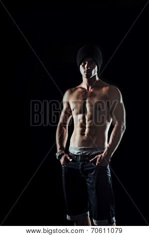 Naked bodybuilder showing his muscles on a black background