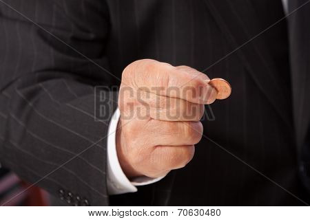 Man's hand pinching penny-horizontal