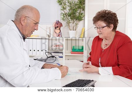 Portrait Of An Older Doctor Talking With His Female Patient.