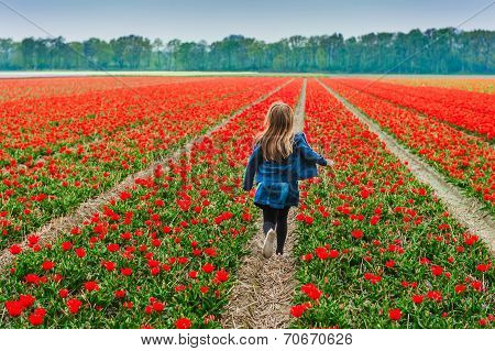 Cute little girl playing in a tulip field