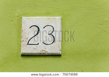 House Number Twenty Three On A Stone Plaque With A Green Wall Background