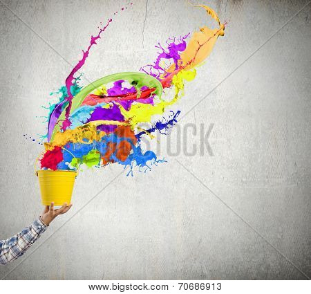 Close up of hand splashing colorful paint from bucket