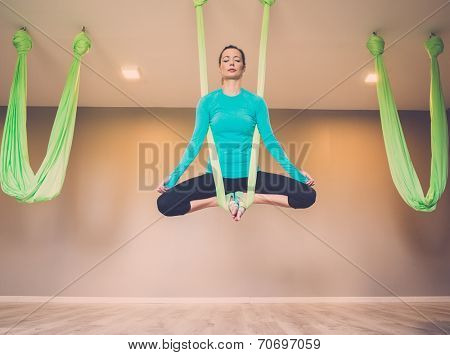 Young woman performing antigravity yoga exercise 
