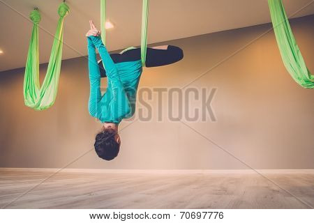 Young woman performing antigravity yoga exercise 
