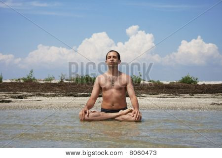 ein Mann sitzt an Land Meer in der Pose des Lotus meditiert