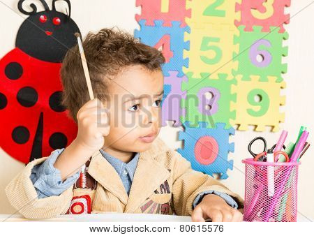 African American Black Boy Drawing With Colorful Pencils In Preschool At Table In Kindergarten