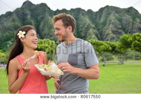 Hawaii food travel couple eating garlic shrimps on Oahu's North Shore. Popular Hawaiian shrimp food truck meal on road trip concept.