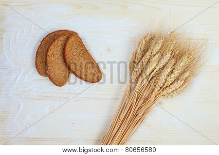 Rustic bread and wheat on an old planked wood table