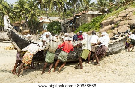 Fishermen Pushing The Fishing Boat On The Beach