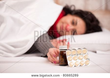 Frustrated woman lying in bed with pills