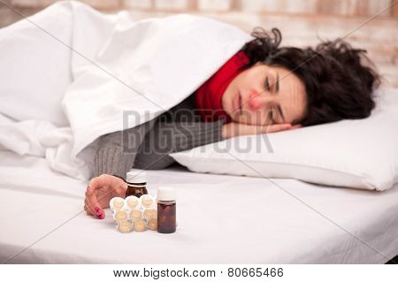 Frustrated woman lying in bed with pills