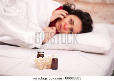 Frustrated woman lying in bed with pills