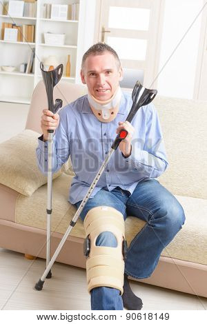 Man with leg in neck brace, knee cages and crutches for stabilization and getting up for rehabilitation