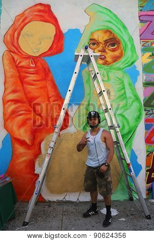 Street artist Bob Plater painting mural at JMZ Walls in Brooklyn