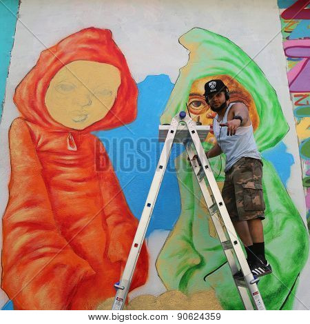 Street artist Bob Plater painting mural at JMZ Walls in Brooklyn