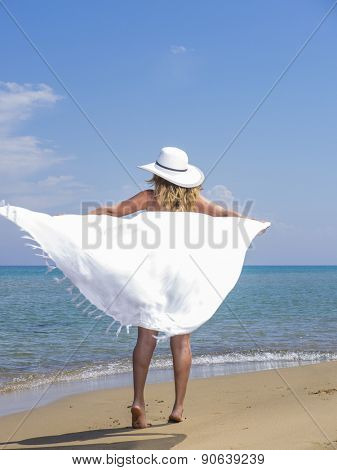 Woman in white sarong and straw hat at the  beach 