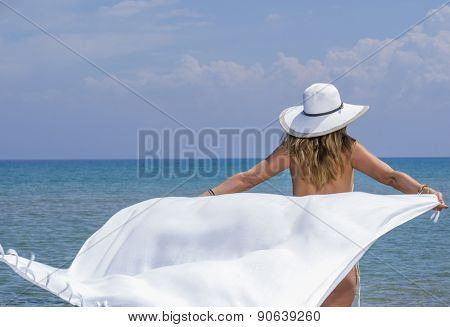 Woman in white sarong and straw hat at the  beach 