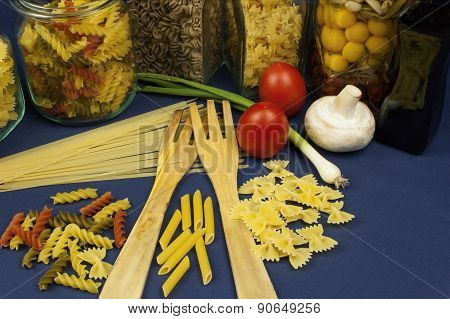 different kinds of pasta on the table, together with vegetables, ready for cooking
