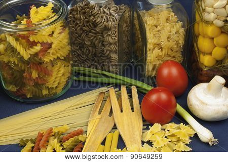 different kinds of pasta on the table, together with vegetables, ready for cooking