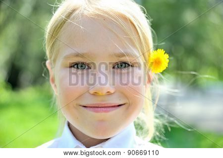 Pretty blone girl outdoors with flower behind ear