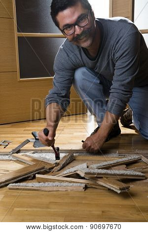 Vertical image of a worker disassembling wooden floor ruined from moisture and water leak