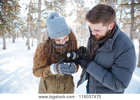 Smiling couple drinking hot tea in winter park