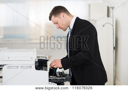 Businessman Adjusting Cartridge In Photocopy Machine