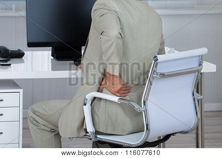 Businessman Suffering From Backache While Sitting On Chair