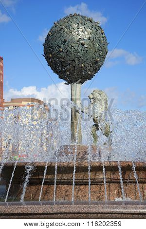 Of orange tree and a lion in the jets of water. Sculpture in the center of the fountain in the town