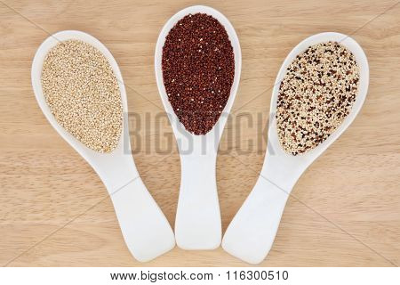 Quinoa health food varieties in porcelain scoops over beech wood background. 