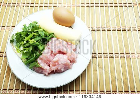 Raw material for clear soup with bean curd and minced pork with egg on brown bamboo mat.