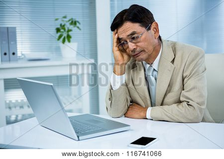 Undecided businessman looks his computer in his office