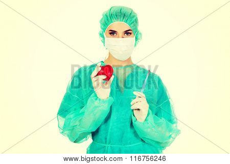 Young female cardiologist surgeron holding heart and scalpel