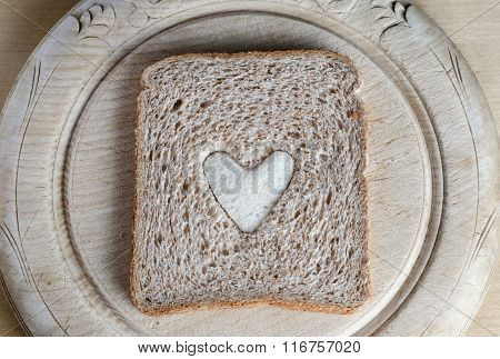 Slice Of Brown Bread With White Heart On Vintage Bread Board