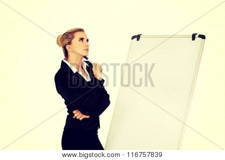 Thinking business woman standing nex to the white board