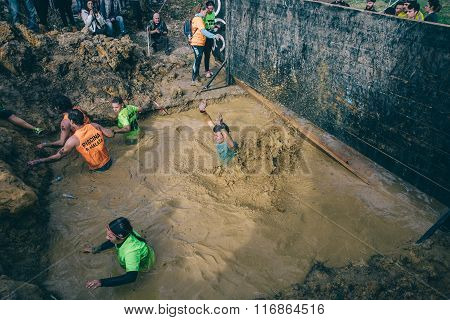 Runners crossing mud pit in a test of extreme obstacle race
