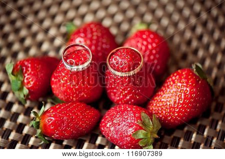 Wedding rings on red juicy strawberries