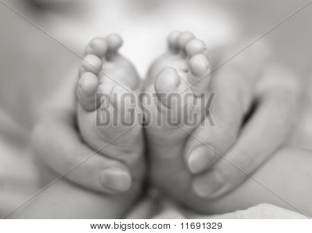 Matka jemně v ruce držet nohy Baby