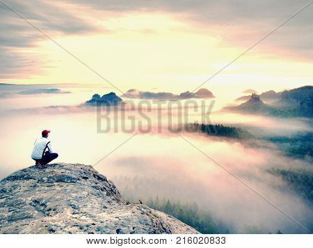 Young Hiker In White And Black Siuts  On Cliff Edge Looking To Misty Hilly Valley Bellow, Fall Begin