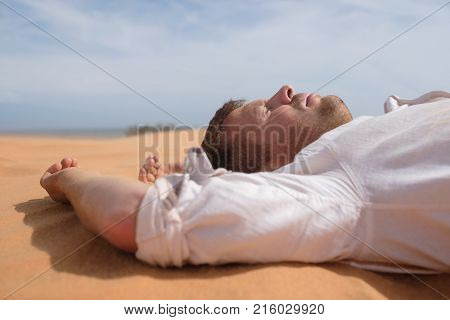 Man lie alone in the sunny desert. He is lost and out of breath. No water and energy. Concept for depression and noway situation in life