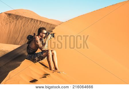 Lonely man photographer sitting on sand at Dune 45 in Sossusvlei - Concept of wanderlust in namibian famous desert - Adventure trip travel to african wonders in Namibia - Soft teal and orange filter