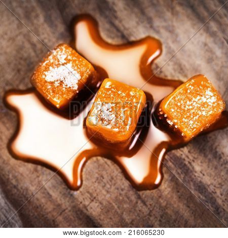 Homemade salted caramel pieces on wooden background. Golden Butterscotch toffee candy caramels with copyspace