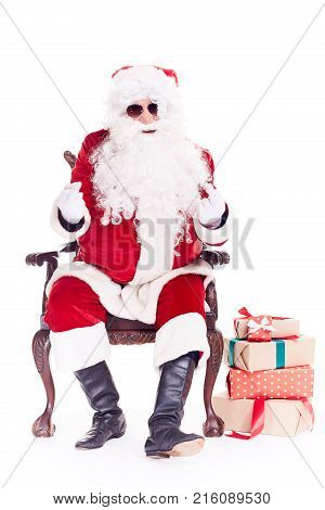 Portrait of swaggy Santa Claus in sunglasses relaxing in chair on white background