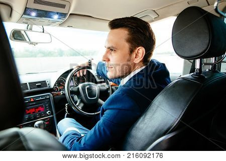 Handsome elegant serious man drives a car