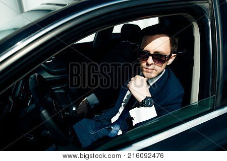 Young cut businessman wearing suite driving car