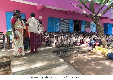 PONDICHERY PUDUCHERY INDIA - SEPTEMBER 04 2017. Outdoor meeting of the children of the school with uniforms sitting on the floor waiting for sport equipments as a gift from an association.