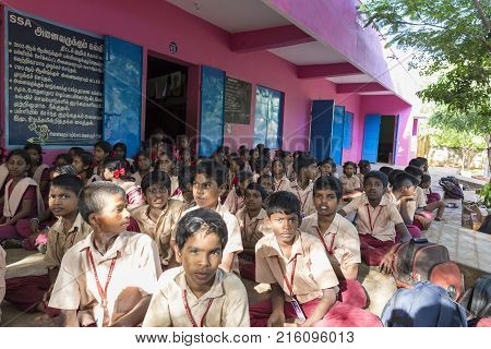 PONDICHERY PUDUCHERY INDIA - SEPTEMBER 04 2017. Outdoor meeting of the children of the school with uniforms sitting on the floor waiting for sport equipments as a gift from an association.