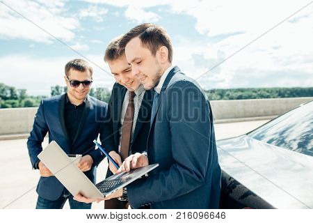 three Businessman Using Digital Tablet Outside against car.