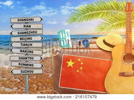 Concept of summer traveling with old suitcase and China town sign with burning sun