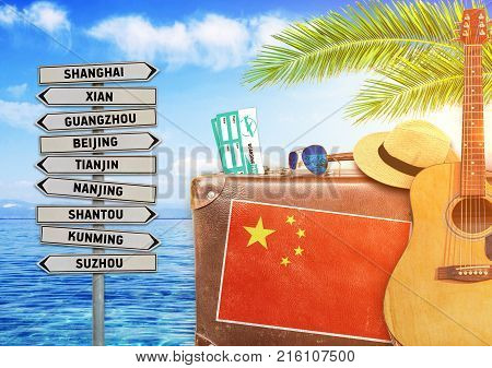 Concept of summer traveling with old suitcase and China town sign with burning sun